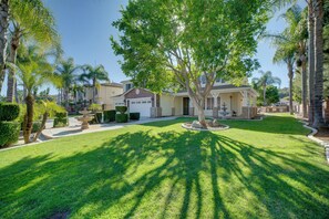 A residential property with a well-maintained lawn, a large tree, and a brick house with a garage. - Resort-Style Oasis: Expansive Riverside Mansion (Riverside)