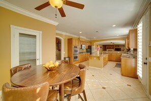 A spacious kitchen with wooden cabinets, a central island, and a dining area with a wooden table and chairs. - Resort-Style Oasis: Expansive Riverside Mansion (Riverside)