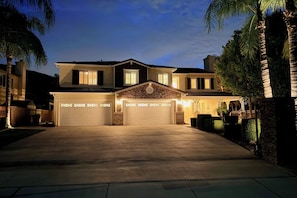 A two-story house with a garage, a stone facade, and a well-lit driveway. - Resort-Style Oasis: Expansive Riverside Mansion (Riverside)