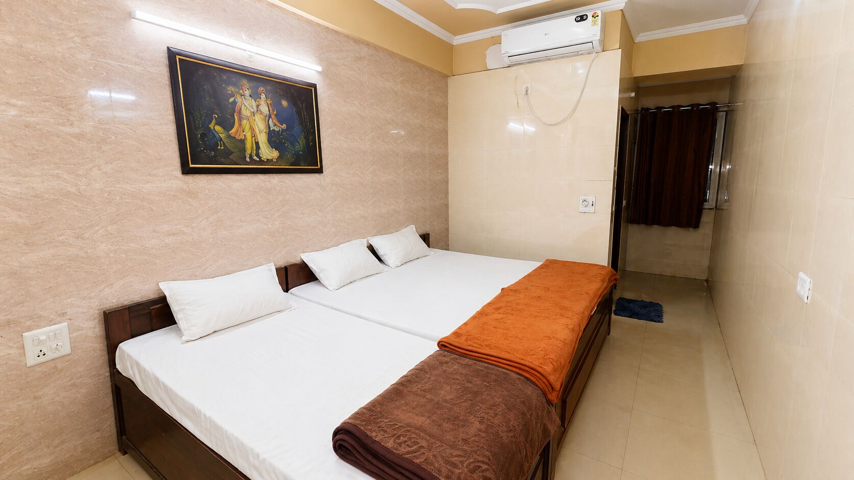 Une chambre d’hôtel comprenant un lit, un tableau, un appareil de climatisation et un espace douche.