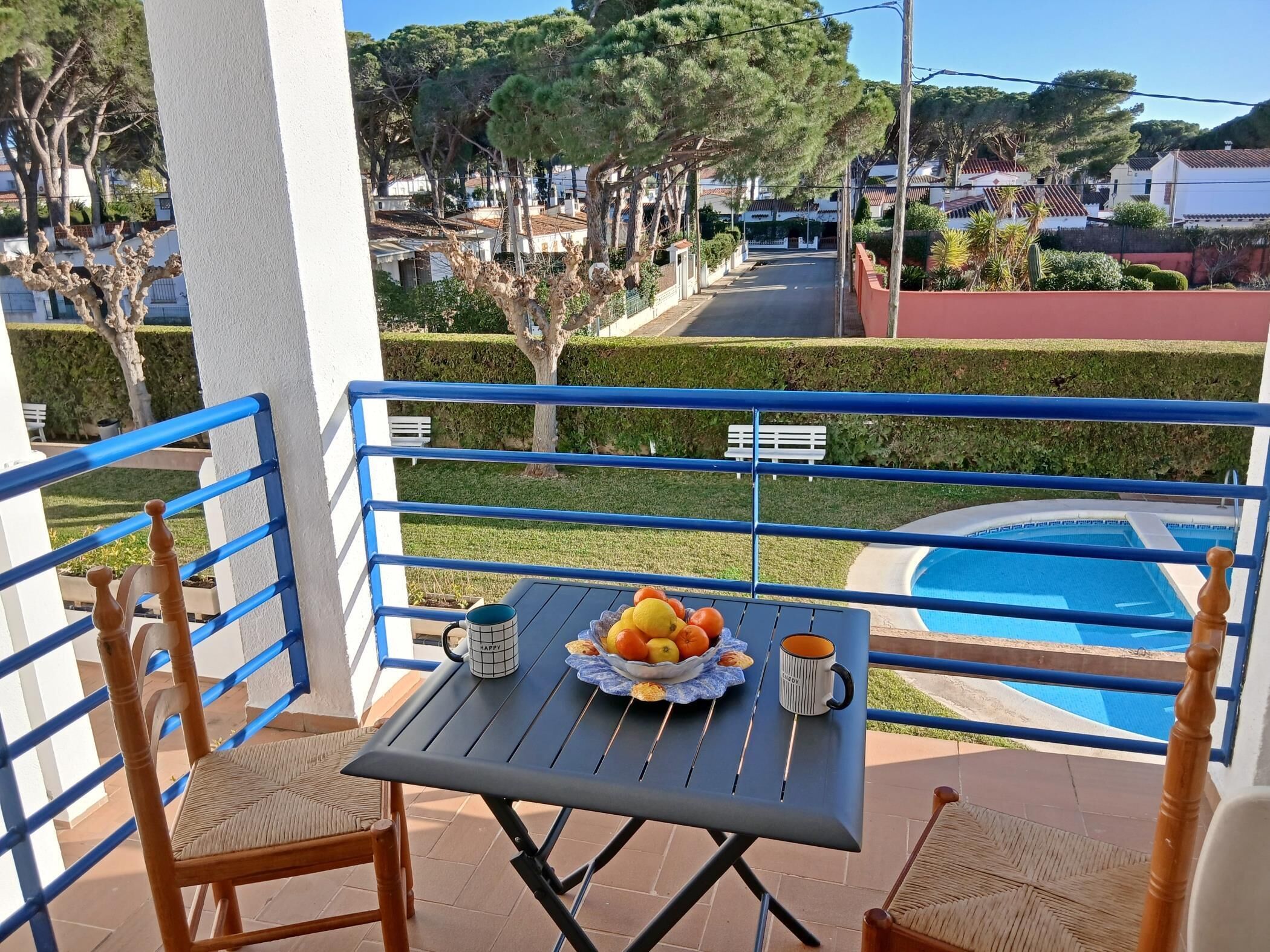 Ein Balkon mit Frühstückstisch, mit Blick auf einen Pool und eine Wohngegend.