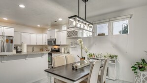 A modern kitchen with white cabinetry, a dark countertop, and a hanging light fixture. - Fenced Yard & Fire Pit! Kennewick Family Retreat (Kennewick)