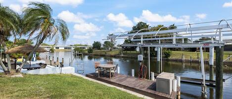 Un muelle con una mesa y sillas, un cuerpo de agua y un puente.