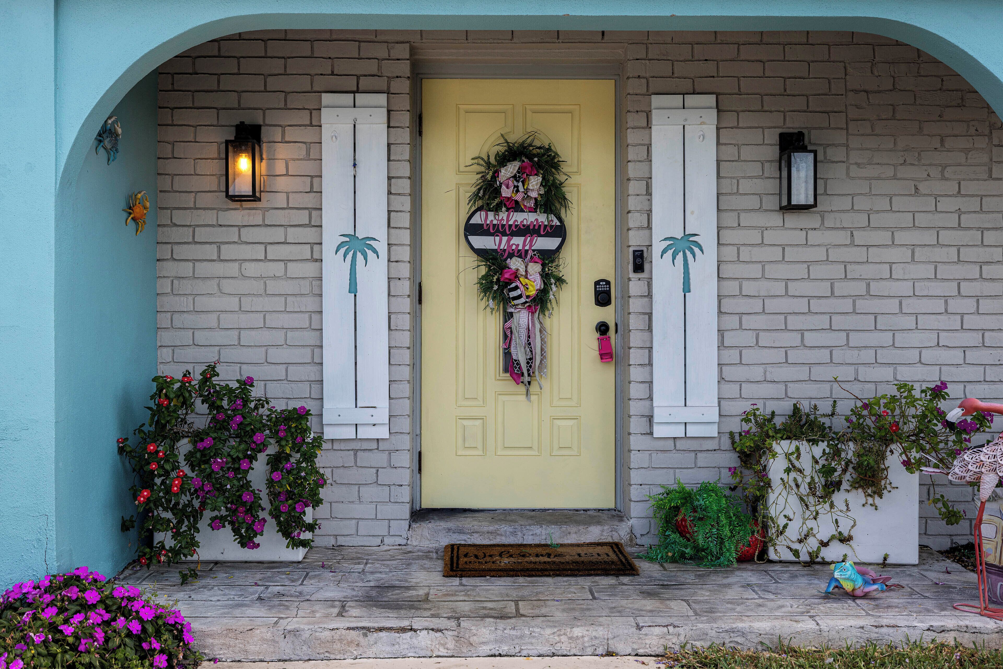A yellow door with a welcome sign, a doormat, and a mailbox.