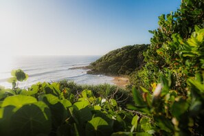 A coastal landscape with a beach, vegetation, and a clear sky. - SeaRenity Coolum Beach (Coolum Beach)
