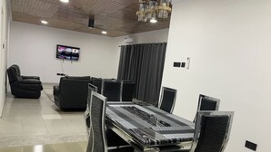A conference room with a long table, black chairs, a sofa, and a television on the wall. - Tree fort property 2 in North Legon (Accra)