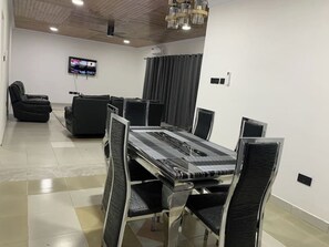 A conference room with a long table, black chairs, a sofa, and a television on the wall. - Tree fort property 2 in North Legon (Accra)