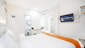 Quarto de hotel com cama, televisão fixada na parede, banheiro com espelho e ar condicionado.