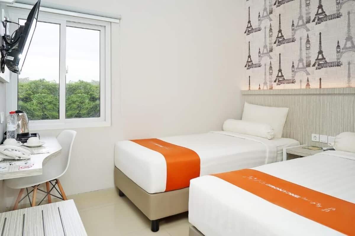 Una habitación de hotel con dos camas, un escritorio y una ventana.