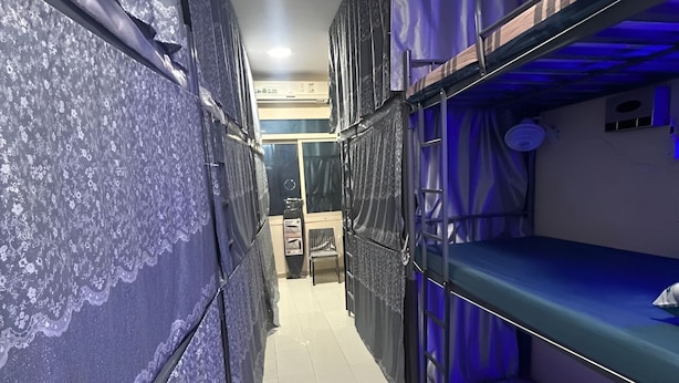 A narrow corridor with bunk beds on both sides, a tiled floor, and a ceiling light. - OST Diera Market Homes (Dubai)