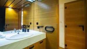 Een moderne badkamer met een wastafel met twee kommen, houten kastjes en een grote spiegel.