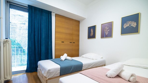 Een slaapkamer met twee bedden, een houten garderobe en een raam met blauwe gordijnen.