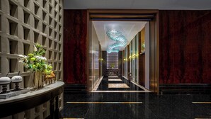 Ein luxuriöser Flur mit Marmorboden, einer Wandverkleidung und einer Chandelier.