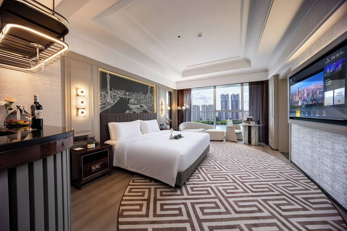 Habitación de hotel moderna con una cama grande, un escritorio y vistas a la ciudad.
