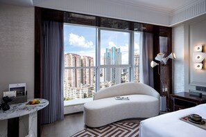 A hotel room with a large window, a curved sofa, a bedside table with a fruit bowl, and a lamp. - Elegant Hotel Guagnzhou Ersha Island (Guangzhou)