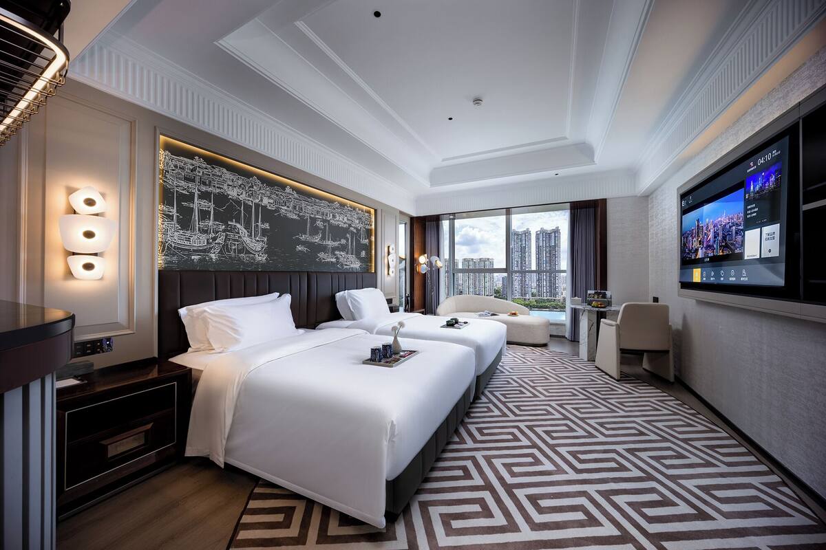 Habitación de hotel con una cama grande, un escritorio, un televisor y vistas a la ciudad.