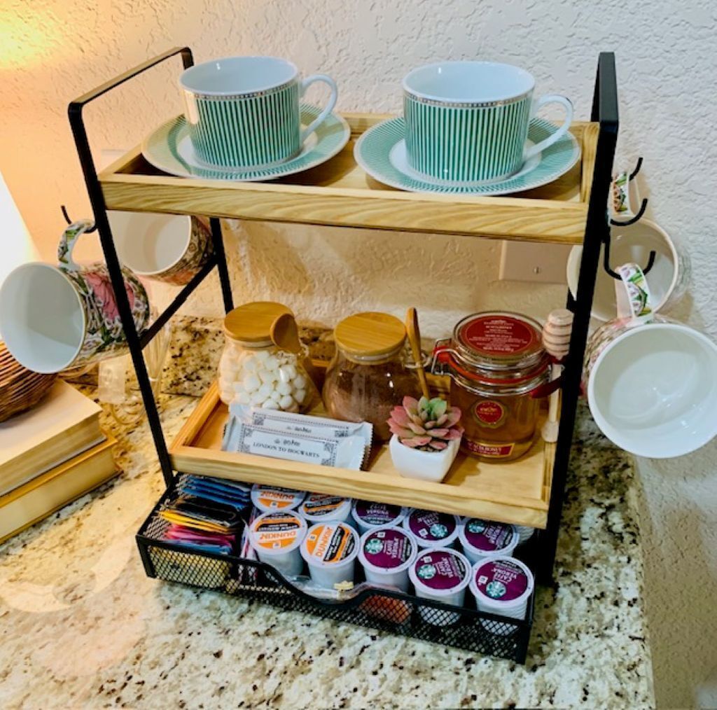 A wooden tray with tea cups, honey jars, and tea bags.
