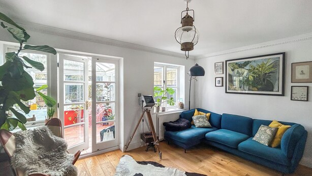 Ein Wohnzimmer mit einem blauen Sofa, einem Kuhfellteppich und einer auf einem Stativ befestigten Kamera.