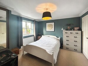 A bedroom with a bed, dresser, and a window with curtains.