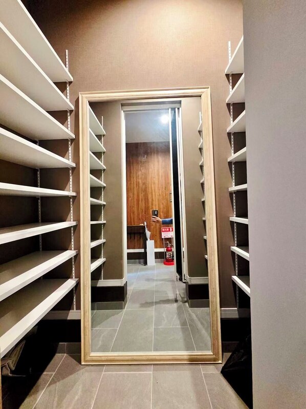 A hallway with a large mirror reflecting a door and a fire extinguisher. Shelves line the walls on both sides. - Yubikan - Newly built 120 sq.m. (with double terrace and parking space) (大阪市)
