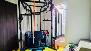 Een sportschool met een pull-up bar, een gewichtbank en diverse fitnessapparaten.