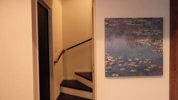 A staircase with a handrail leading to a landing, and a painting of water lilies on the adjacent wall.