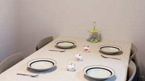 Ruokapöytä on katettu lautasilla, aterimilla ja siinä on koriste-esine.