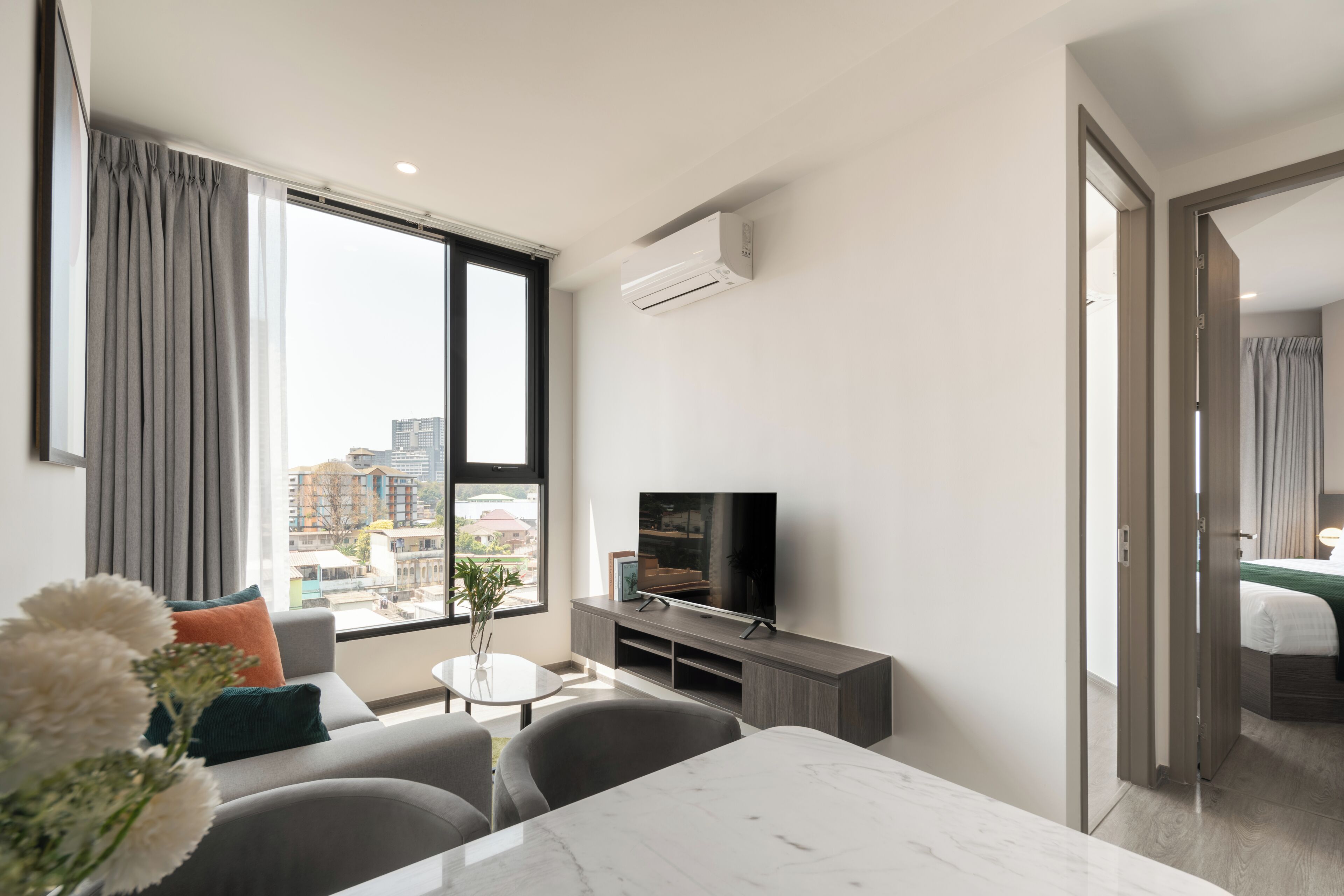 Habitación de hotel moderna con un ventanal grande, televisor de pantalla plana, una mesa de comedor y un sofá.