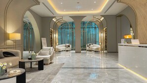 Eine geräumige Lobby mit einer Rezeption, zwei Sofas, einem Couchtisch und einem großen Bogenfenster.