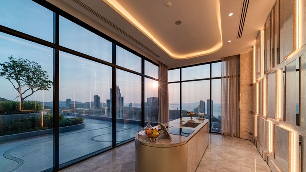 Ein modernes Hotelzimmer mit großen Fenstern, einer geschwungenen Rezeption und Blick auf die Stadt.