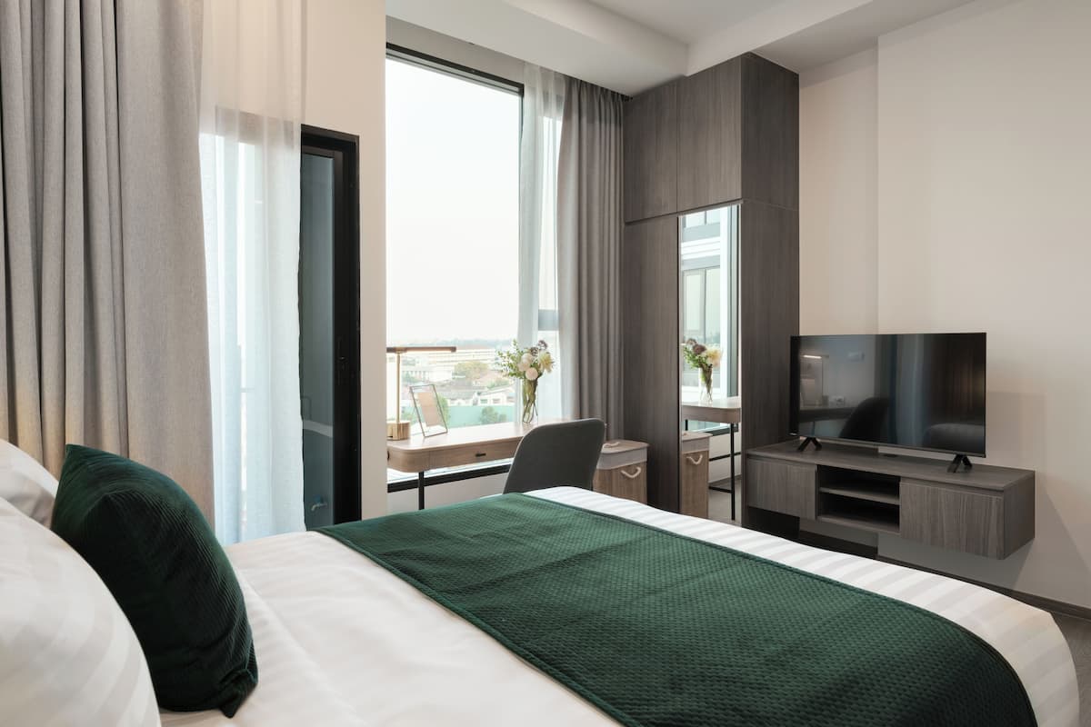 A hotel room with a bed, a desk, a television, and a window with a view.