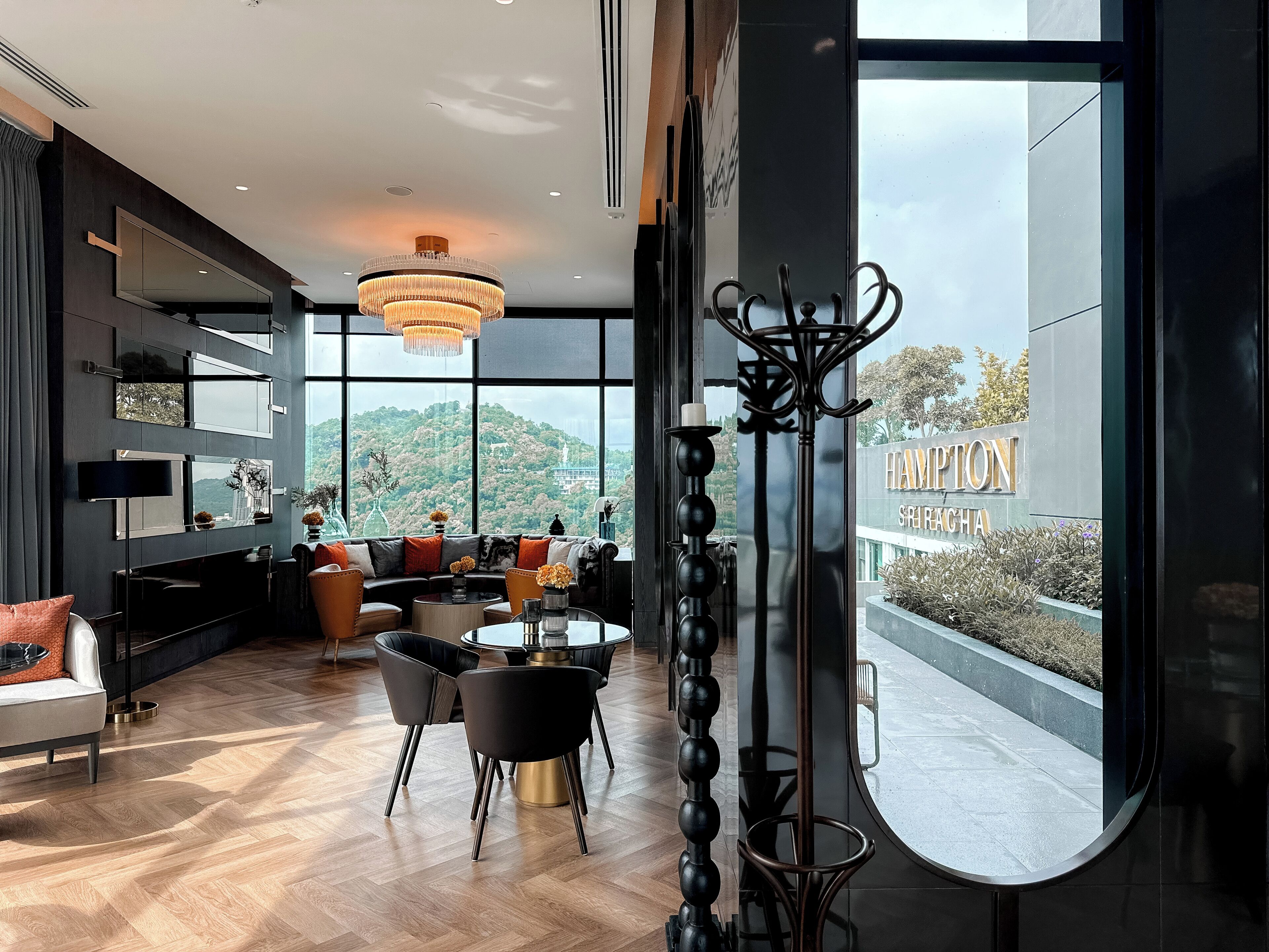A modern hotel interior with a large window, a dining area, and a view of the surrounding landscape.