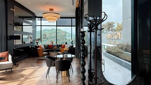 Ein modernes Hotelzimmer mit einem großen Fenster, einem Essbereich und Blick auf die umliegende Landschaft.