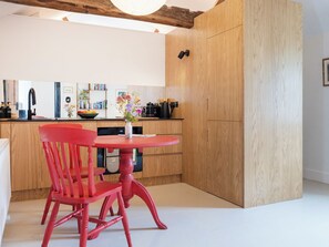 Una cocina moderna con armarios de madera, una silla roja, una mesa redonda y un florero con flores.