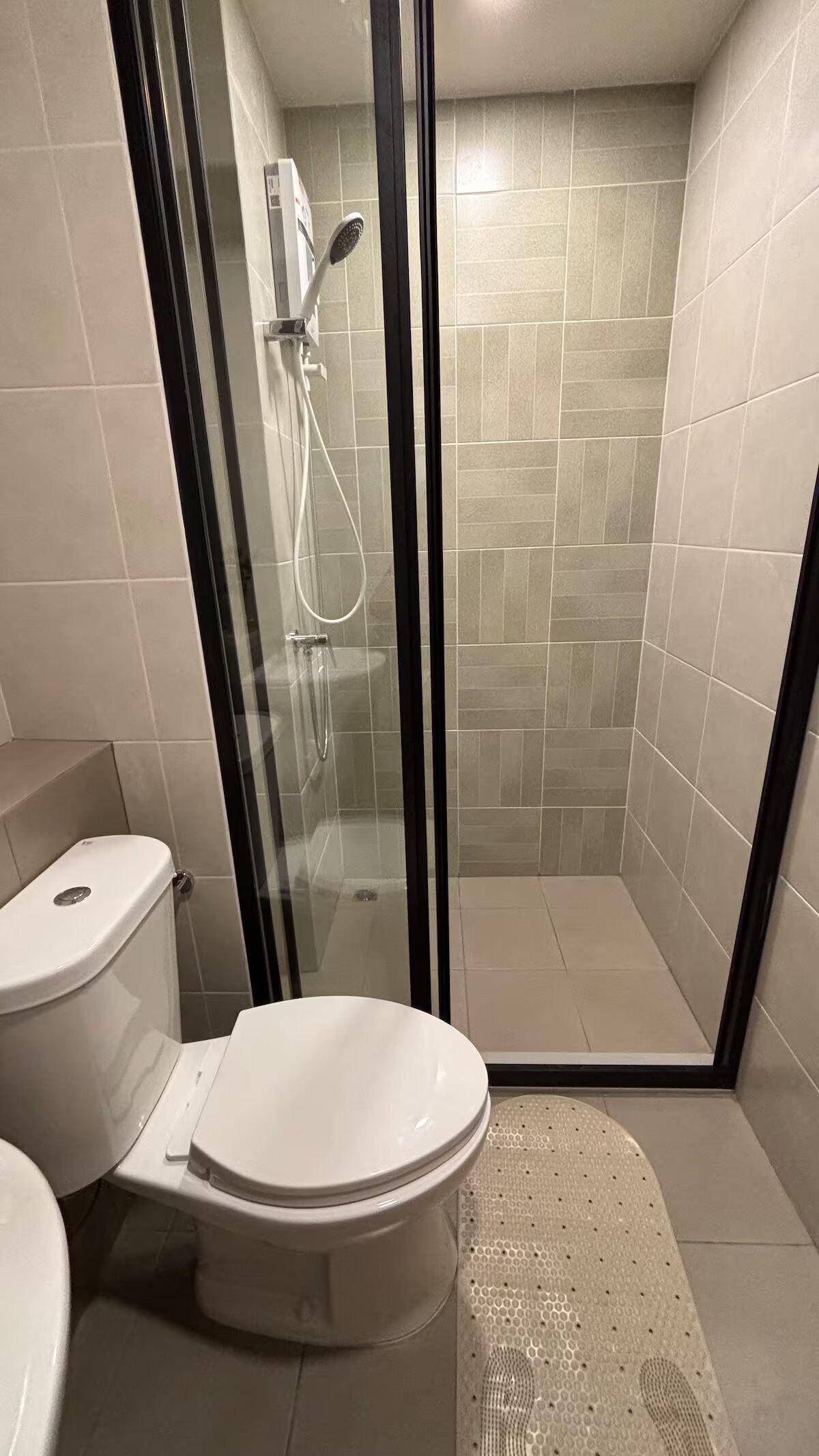 A bathroom with a toilet, a shower enclosure, and tiled walls.