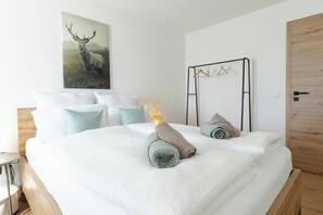 A bedroom with a bed, pillows, a wall-mounted light, a wooden door, and a coat rack. - Simon vacation apartment, 90 m², 2-6 persons, eat-in kitchen, 3 bedrooms, shower/WC + WC, balcony (Staudach-Egerndach)