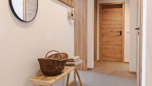 Un couloir avec un banc en bois, un miroir et un porte-manteau.