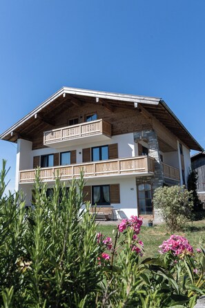 Ein mehrstöckiges Gebäude mit Balkonen, einer Steinfassade und blauem Himmel im Hintergrund.