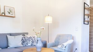 Un salon moderne avec un canapé gris, une table basse ronde et un fauteuil bleu.