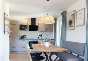 A modern kitchen with a dining area, including a wooden table, chairs, and a sofa. - Simon vacation apartment, 90 m², 2-6 persons, eat-in kitchen, 3 bedrooms, shower/WC + WC, balcony (Staudach-Egerndach)