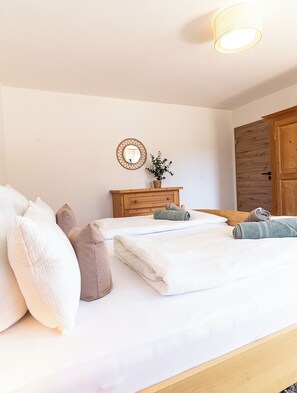 Une chambre à coucher avec un lit, des oreillers, une commode, un miroir et une porte.