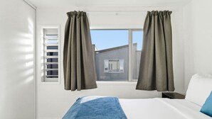 Ein Hotelzimmer mit einem Bett, einem Fenster mit Jalousien und Vorhängen.