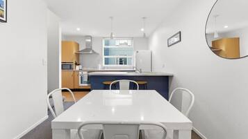 A modern kitchen with white cabinets, a central island, and a dining area with a white table and chairs.