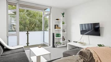 A modern living room with a sofa, a coffee table, a TV, and a bookshelf.