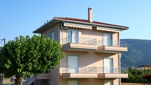 A two-story building with a stone base, a balcony on the upper floor, and a tree in the foreground. - Villa Eudora Nafpaktos (Nafpaktos)
