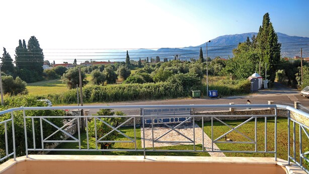 A balcony with a view of a green landscape, a road, and distant mountains. - Villa Eudora Nafpaktos (Nafpaktos)
