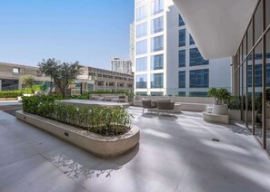 A rooftop terrace with seating areas, planters, and a view of surrounding buildings. - Free housekeeping visits during your stay - StayShort - Elegant Studio in JVC that Sleeps 2 (Jumeirah Village Circle)