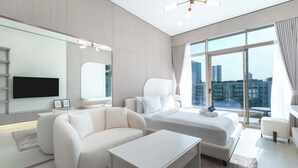 Een moderne hotelkamer met een groot bed, een slaapbank, een flatscreen televisie en uitzicht op de stad door grote ramen.