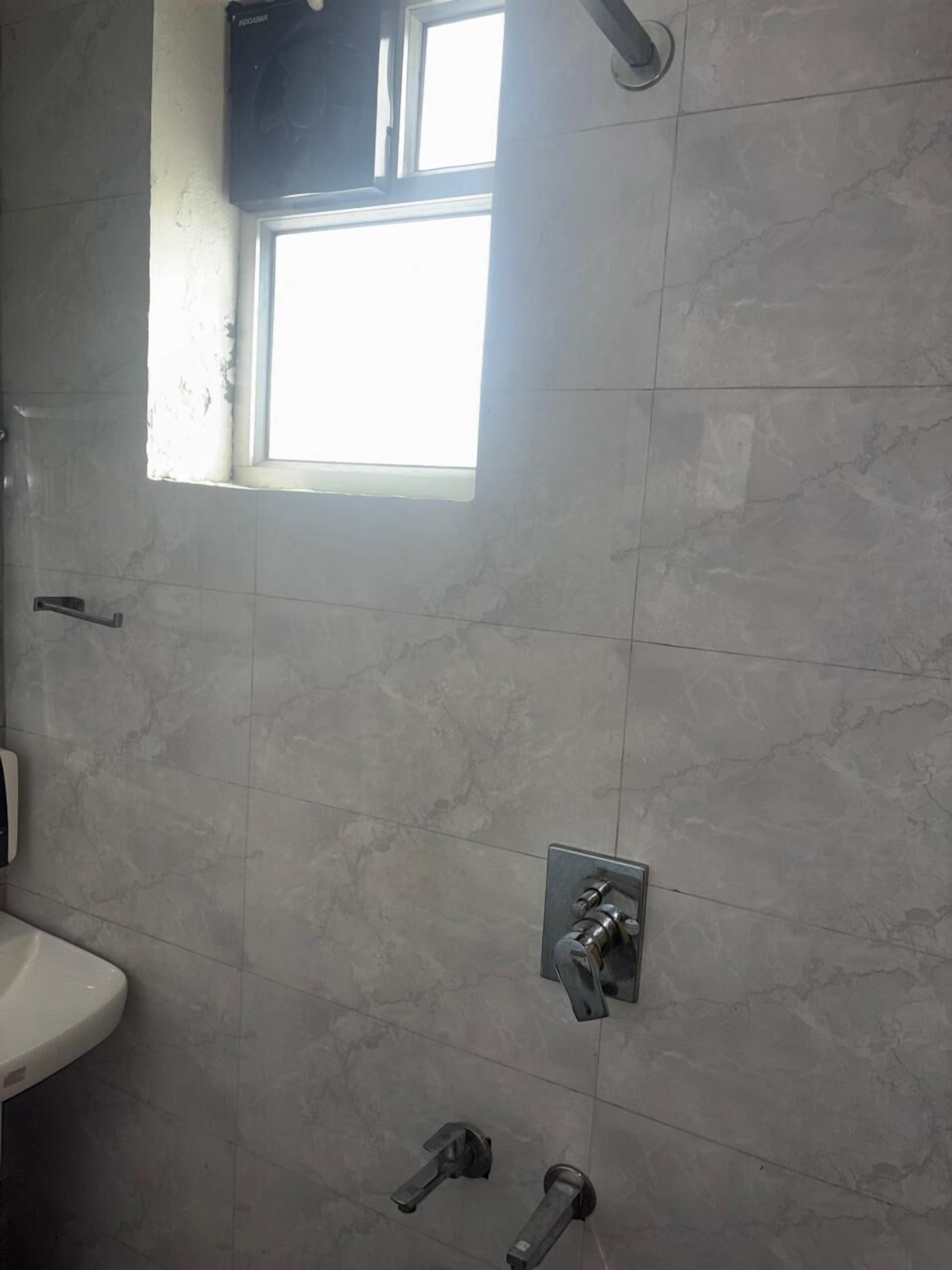 Un baño con ventana, lavamanos y zona de ducha.