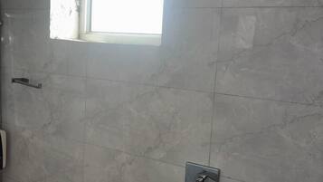 Un baño con ventana, lavamanos y zona de ducha.